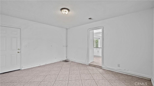 empty room with light tile patterned floors and a textured ceiling