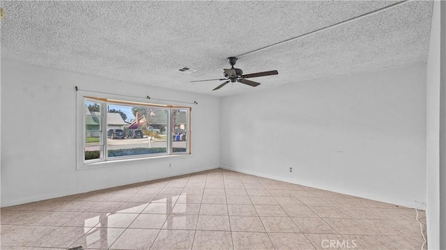 unfurnished room featuring ceiling fan, light tile patterned flooring, and a textured ceiling