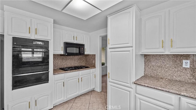 kitchen with black appliances, light tile patterned flooring, white cabinetry, and tasteful backsplash