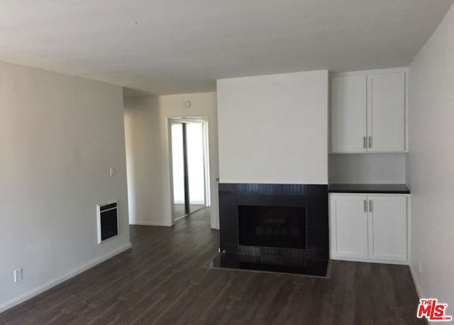 unfurnished living room featuring heating unit and dark hardwood / wood-style floors