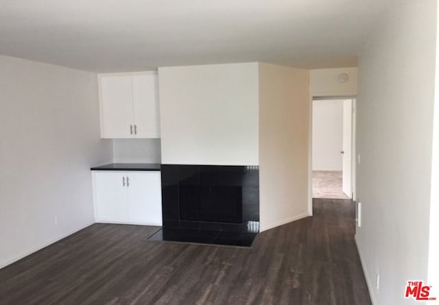 unfurnished living room featuring a fireplace and dark hardwood / wood-style floors