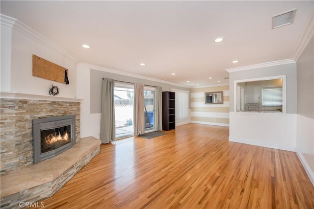 unfurnished living room featuring light hardwood / wood-style floors, a stone fireplace, and ornamental molding