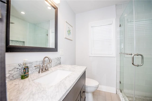 bathroom featuring vanity, toilet, and an enclosed shower