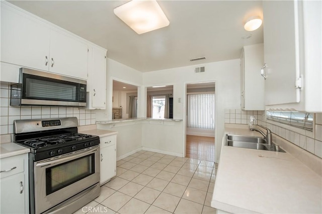 kitchen with appliances with stainless steel finishes, light tile patterned floors, white cabinetry, and sink