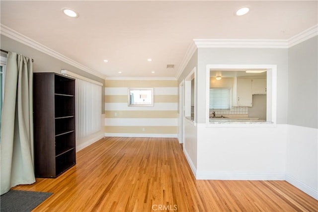 spare room with light wood-type flooring, ornamental molding, and sink