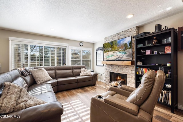 living room featuring a textured ceiling, a fireplace, and light hardwood / wood-style floors