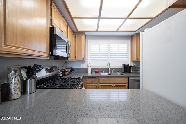 kitchen featuring stainless steel appliances, sink, and dark stone countertops