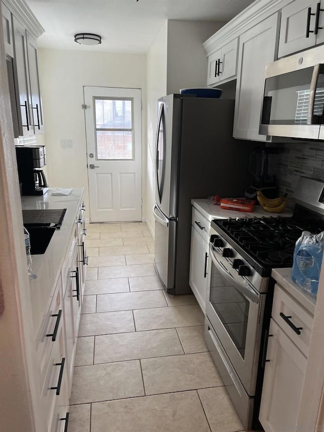 kitchen featuring white cabinetry, sink, tasteful backsplash, light tile patterned floors, and appliances with stainless steel finishes