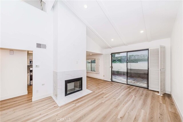 unfurnished living room featuring a multi sided fireplace, high vaulted ceiling, and light hardwood / wood-style flooring