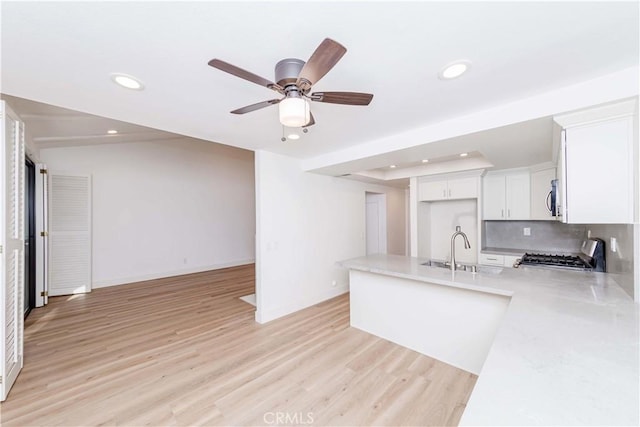 kitchen featuring white cabinetry, stove, sink, and light hardwood / wood-style flooring