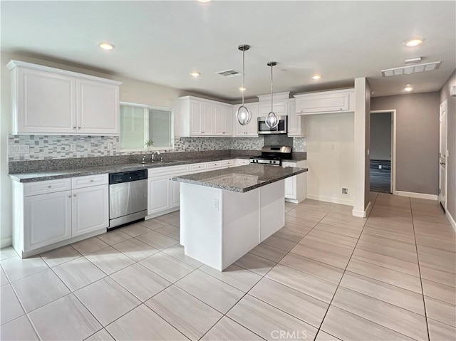 kitchen with sink, stainless steel appliances, a kitchen island, decorative light fixtures, and white cabinets