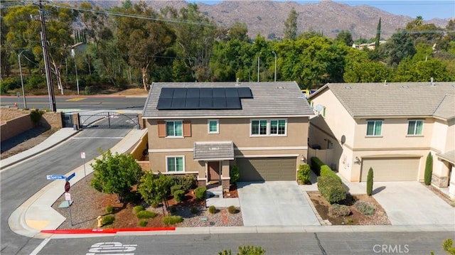 view of front of home featuring solar panels, a garage, and a mountain view