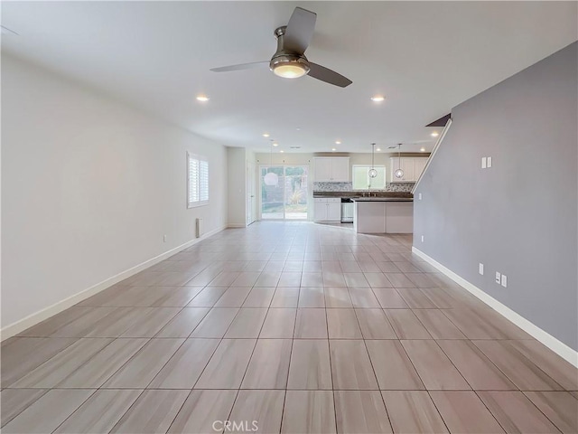 unfurnished living room with ceiling fan and sink