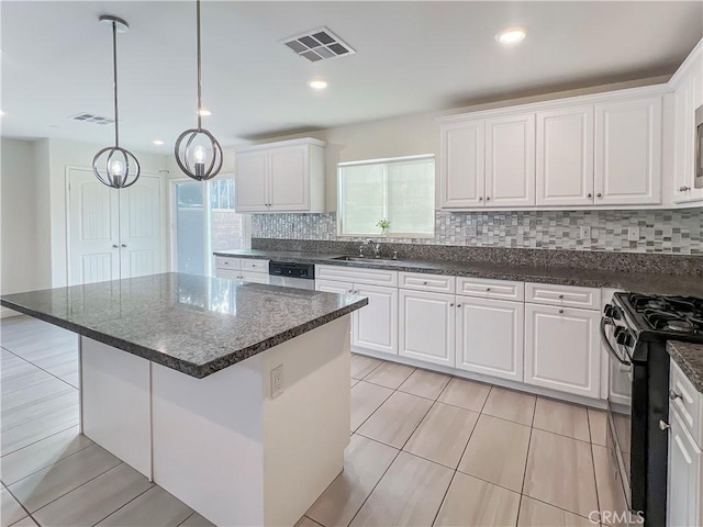 kitchen with tasteful backsplash, white cabinets, black gas range oven, and a kitchen island