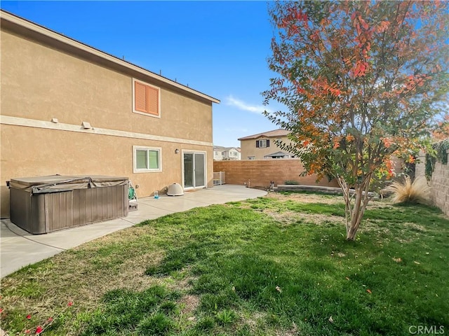 rear view of house featuring a lawn, a patio, and a hot tub