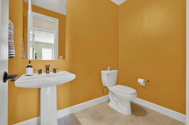 bathroom with toilet, tile patterned flooring, and sink