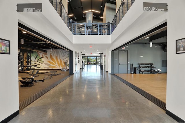 hallway featuring a towering ceiling and concrete floors