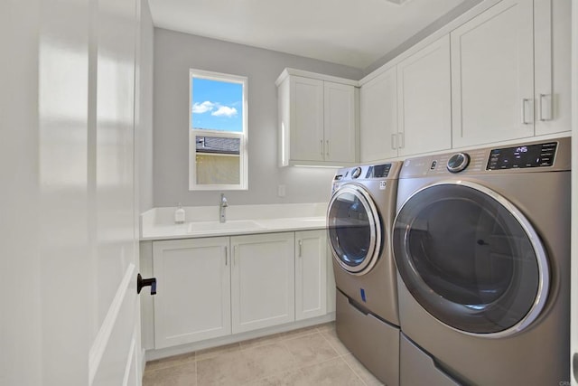 washroom with cabinets, light tile patterned flooring, washing machine and clothes dryer, and sink