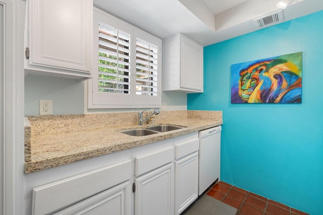 kitchen with dishwasher, white cabinets, sink, dark tile patterned floors, and light stone countertops