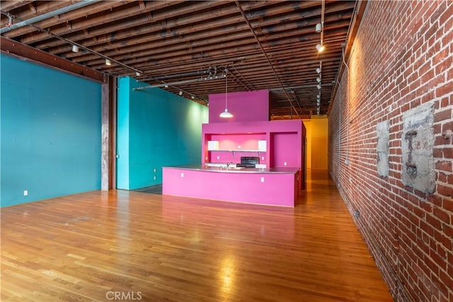 interior space featuring sink, a high ceiling, brick wall, track lighting, and hardwood / wood-style flooring