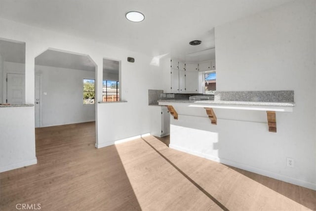 kitchen with kitchen peninsula, light wood-type flooring, and white cabinetry