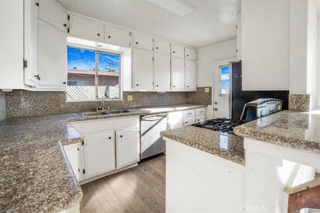 kitchen with dishwasher, dark stone counters, sink, light hardwood / wood-style floors, and white cabinetry