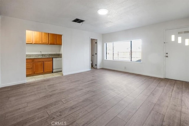 unfurnished living room featuring sink and light wood-type flooring