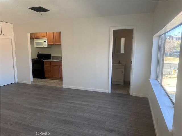 kitchen with black gas range, dark hardwood / wood-style flooring, and a wealth of natural light