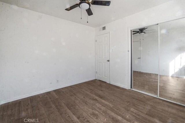 unfurnished bedroom featuring ceiling fan, a closet, and dark wood-type flooring