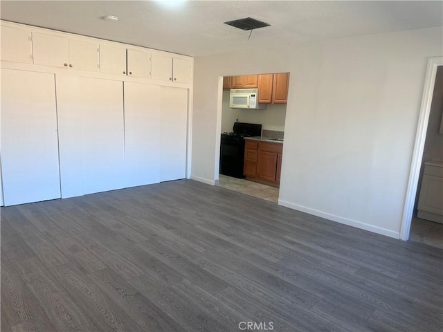 interior space with dark hardwood / wood-style flooring and black range oven