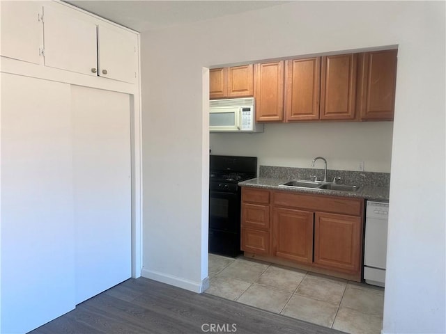 kitchen with white appliances, sink, and light hardwood / wood-style flooring