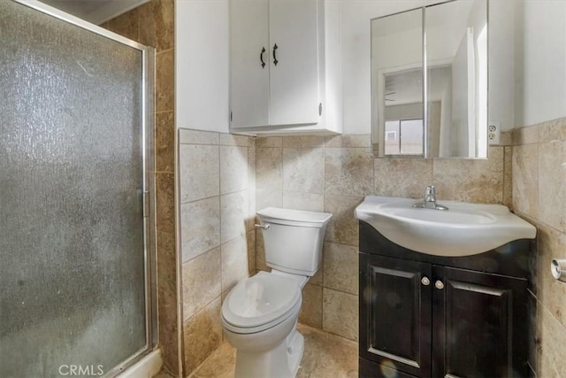 bathroom with vanity, toilet, an enclosed shower, and tile walls