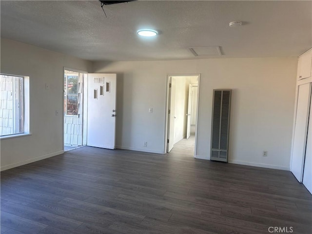 spare room with a textured ceiling and dark hardwood / wood-style floors