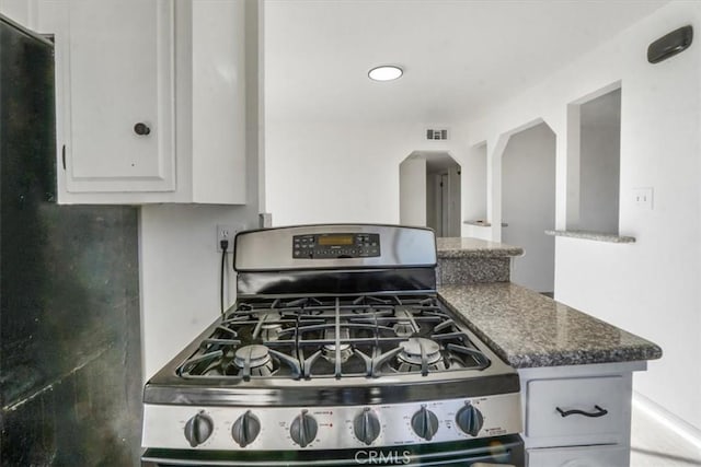 kitchen featuring dark stone countertops, white cabinets, and stainless steel range with gas stovetop