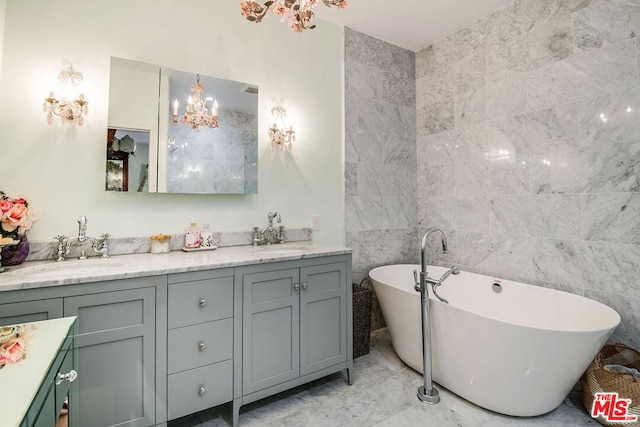 bathroom featuring vanity, an inviting chandelier, tile walls, and a bathing tub