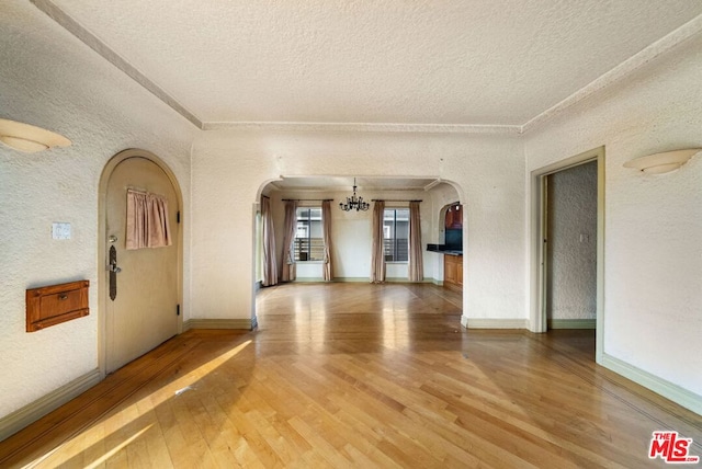 unfurnished room featuring hardwood / wood-style floors, a textured ceiling, and an inviting chandelier