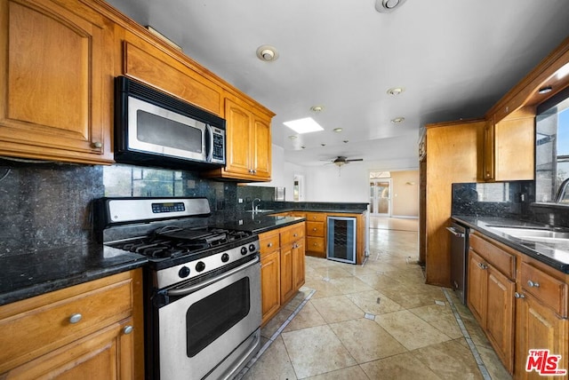 kitchen featuring ceiling fan, sink, beverage cooler, tasteful backsplash, and appliances with stainless steel finishes