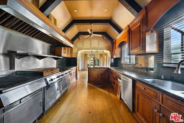 kitchen featuring backsplash, sink, vaulted ceiling, stainless steel dishwasher, and hardwood / wood-style flooring