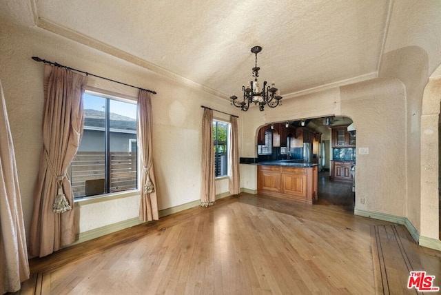 kitchen featuring a wealth of natural light, light hardwood / wood-style flooring, a textured ceiling, and a notable chandelier