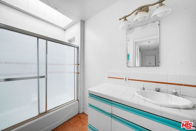 bathroom featuring combined bath / shower with glass door, decorative backsplash, vanity, and tile patterned floors