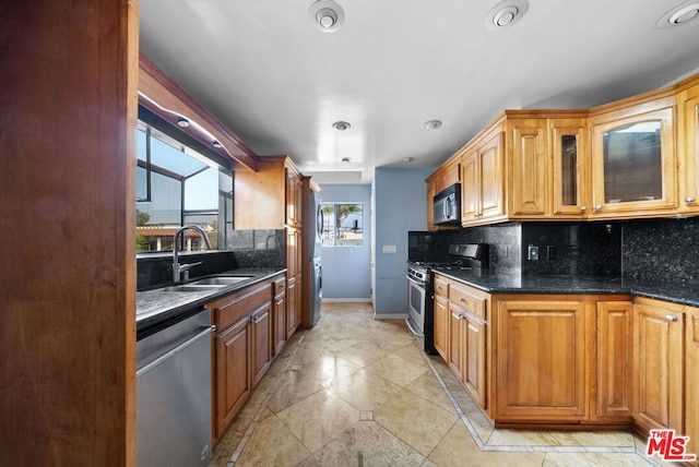 kitchen featuring tasteful backsplash, sink, dark stone counters, and appliances with stainless steel finishes