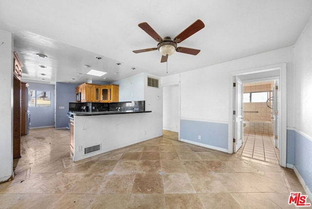 kitchen with a breakfast bar area, kitchen peninsula, ceiling fan, and tasteful backsplash