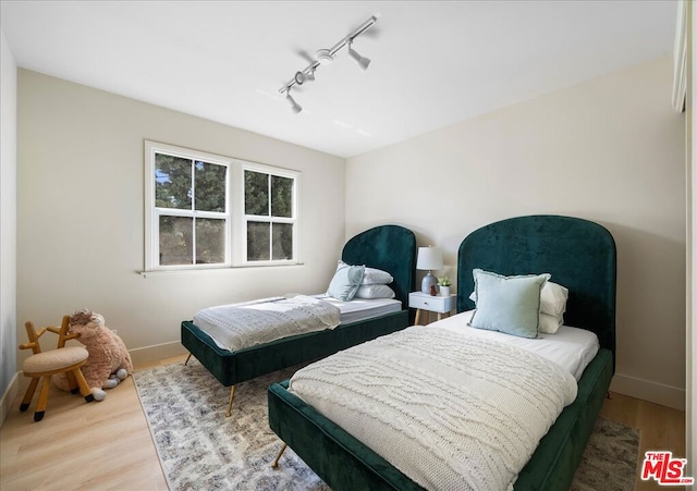 bedroom featuring rail lighting and hardwood / wood-style flooring