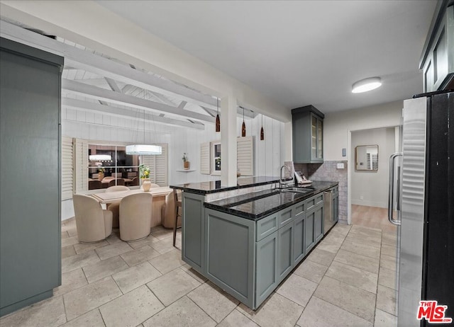 kitchen with gray cabinetry, stainless steel appliances, sink, beam ceiling, and dark stone countertops