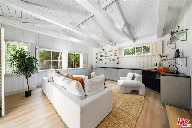 living room with lofted ceiling with beams, sink, a wealth of natural light, and light hardwood / wood-style flooring