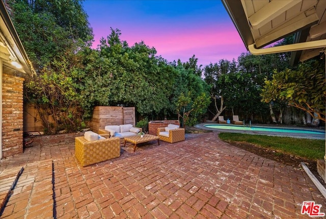 patio terrace at dusk with a fenced in pool and an outdoor living space