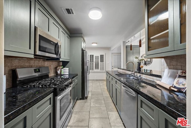 kitchen with tasteful backsplash, sink, appliances with stainless steel finishes, and dark stone counters