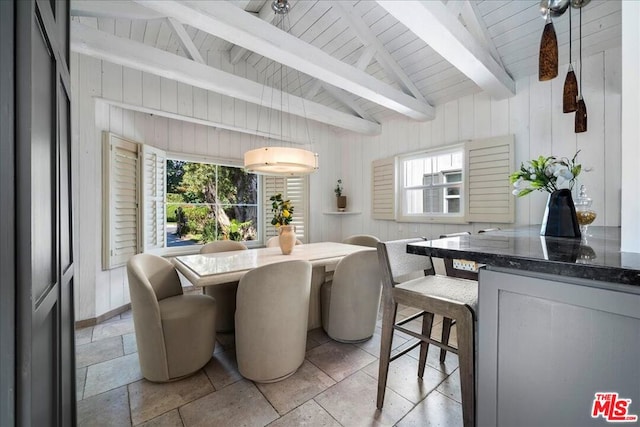 dining room with vaulted ceiling with beams, wooden ceiling, and wooden walls