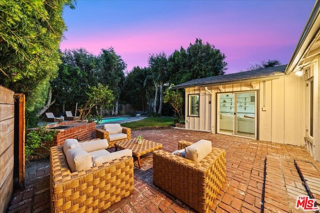 patio terrace at dusk featuring a fenced in pool