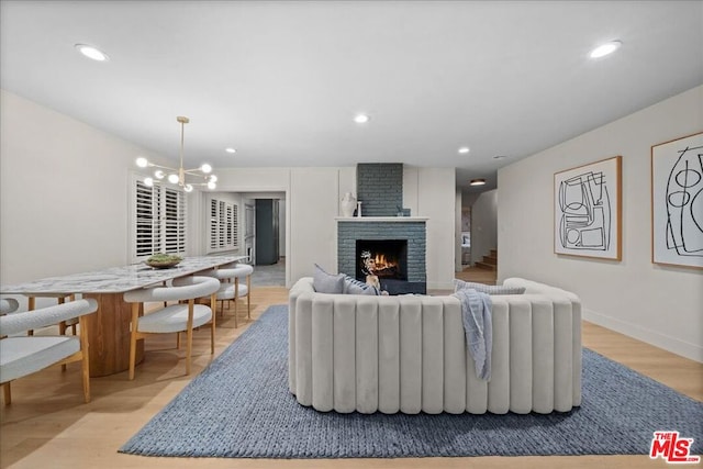 living room with a fireplace, light wood-type flooring, and a chandelier